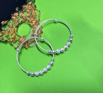 Silver hoop earrings with bead detailing on a green background