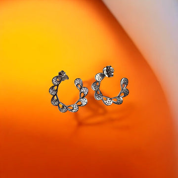 Pair of silver hoop earrings on an orange background