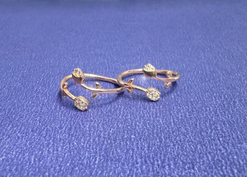 Pair of gold earrings with floral designs on a blue textured background