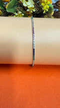 Bracelet with multicolored stones on a wrist against an orange background
