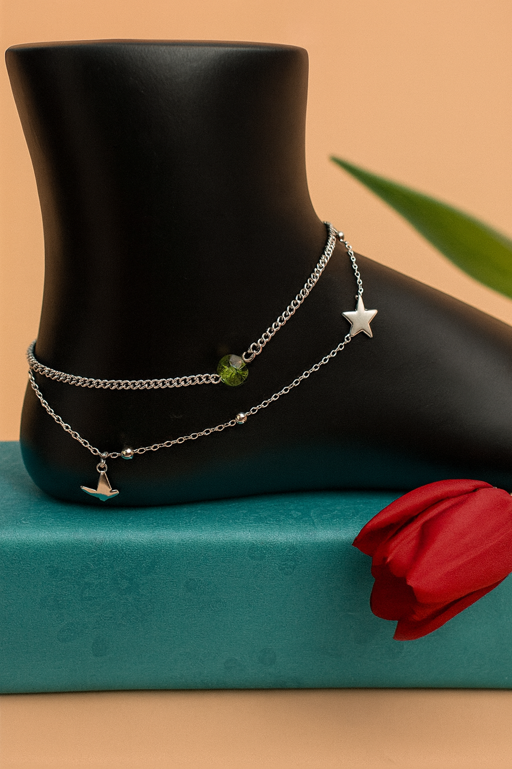 Silver double chain anklet with star and airplane charms on black mannequin