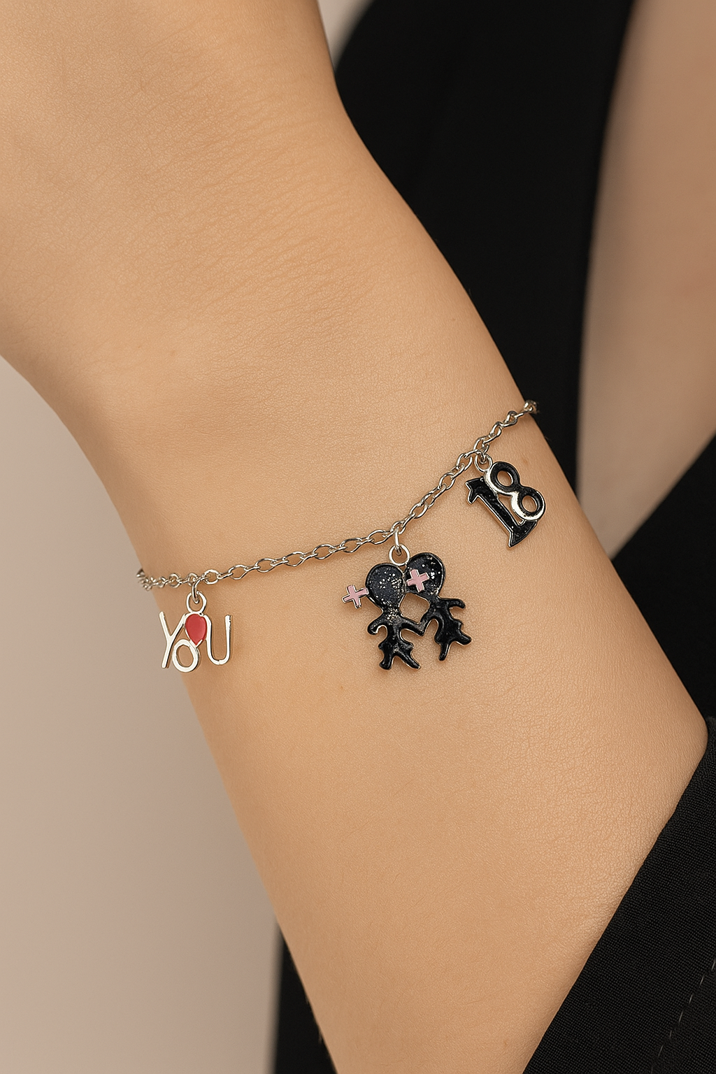 Bracelet with charms on a wrist against a neutral background