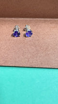 Pair of blue gemstone stud earrings on a brown surface