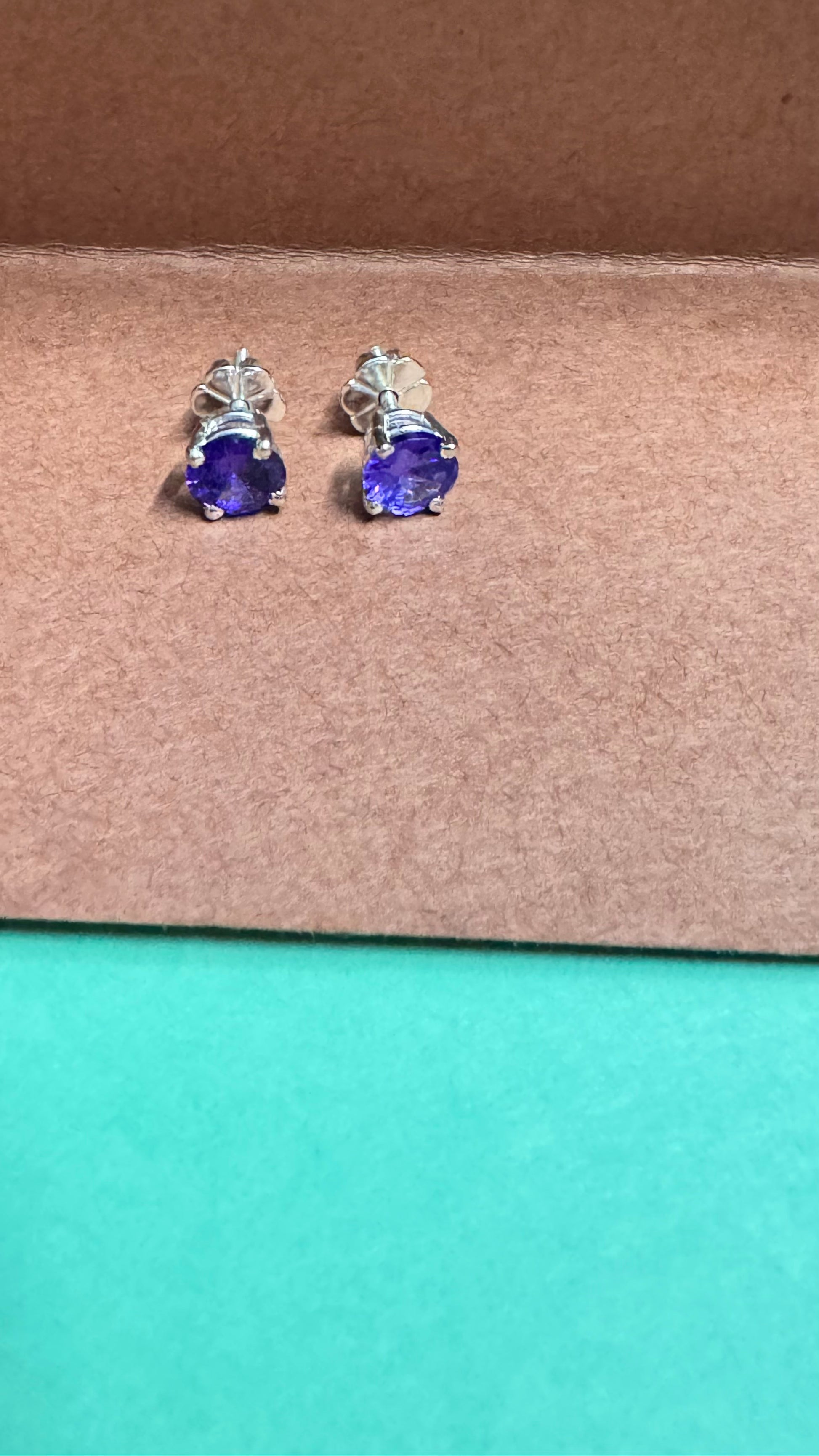 Pair of blue gemstone stud earrings on a brown surface
