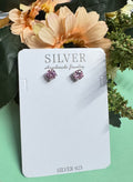 Silver earrings on a card with 'SILVER Handmade Jewelry' text, surrounded by flowers.