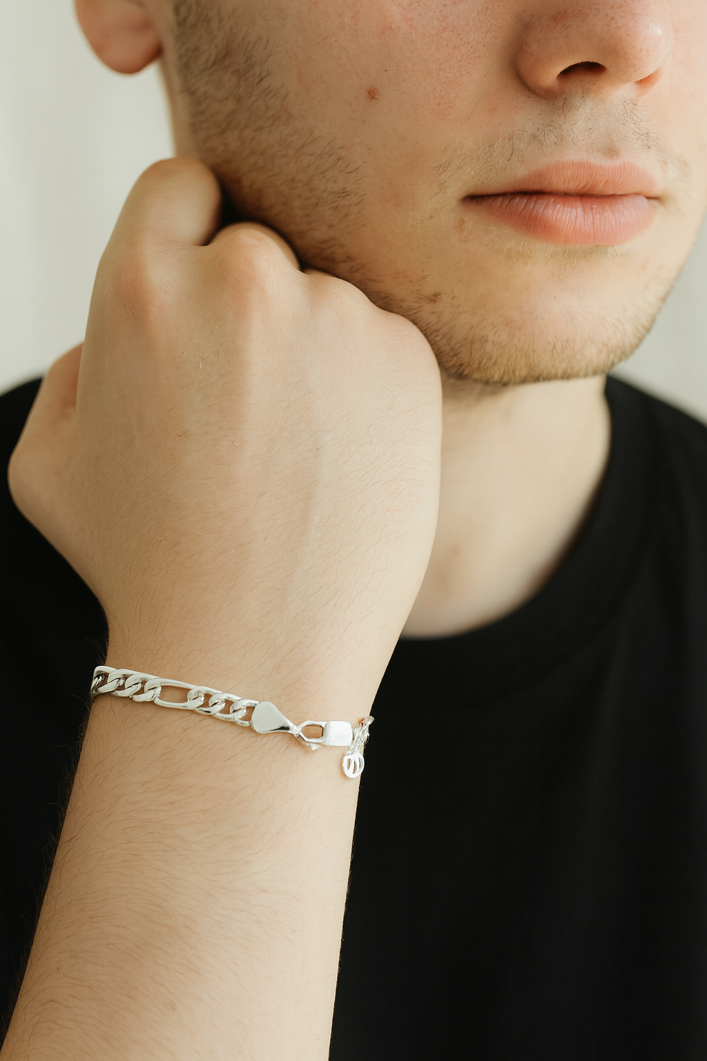 Person wearing a silver chain bracelet on a neutral background