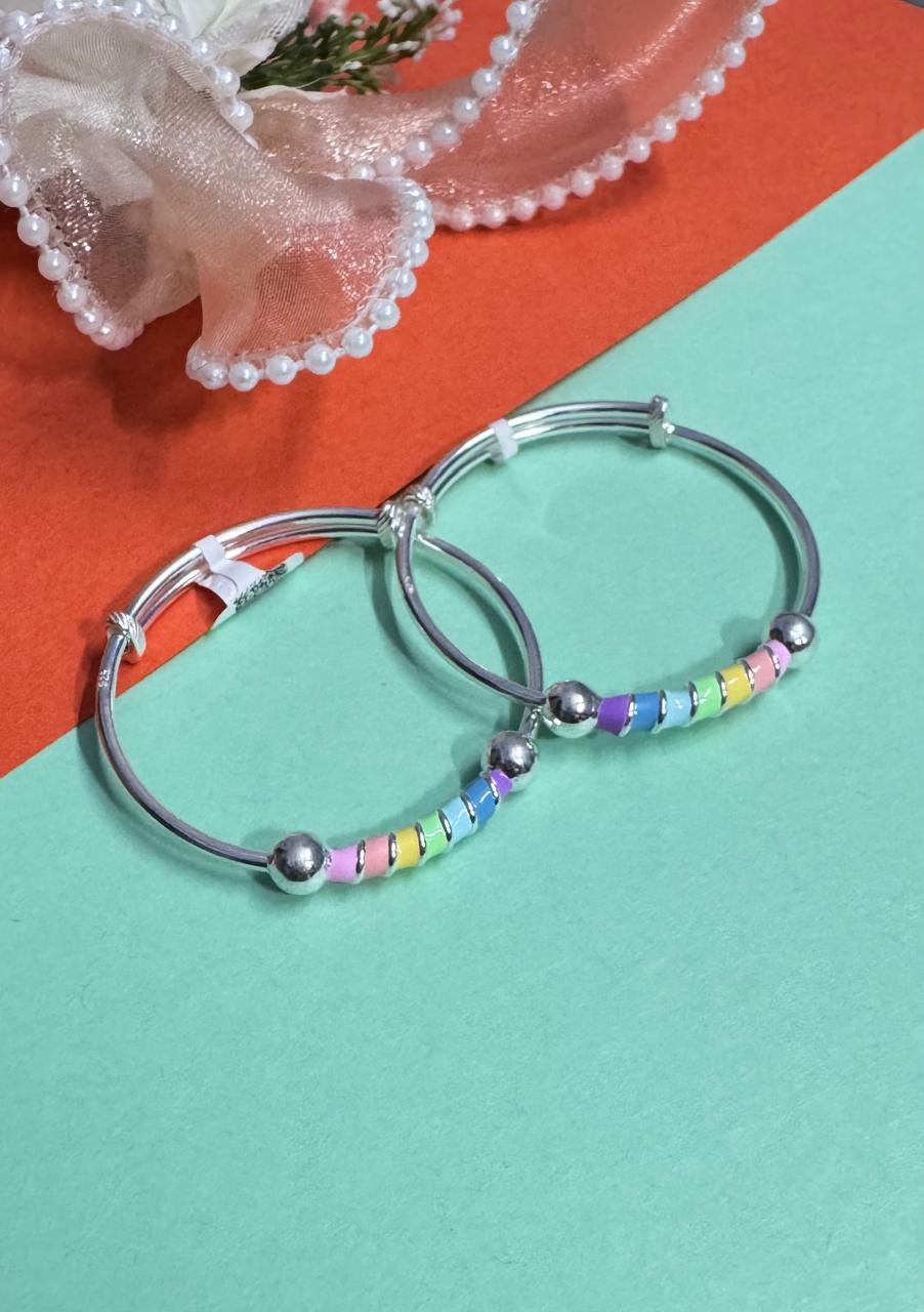 Silver babby kara with colorful beads on a multicolored background