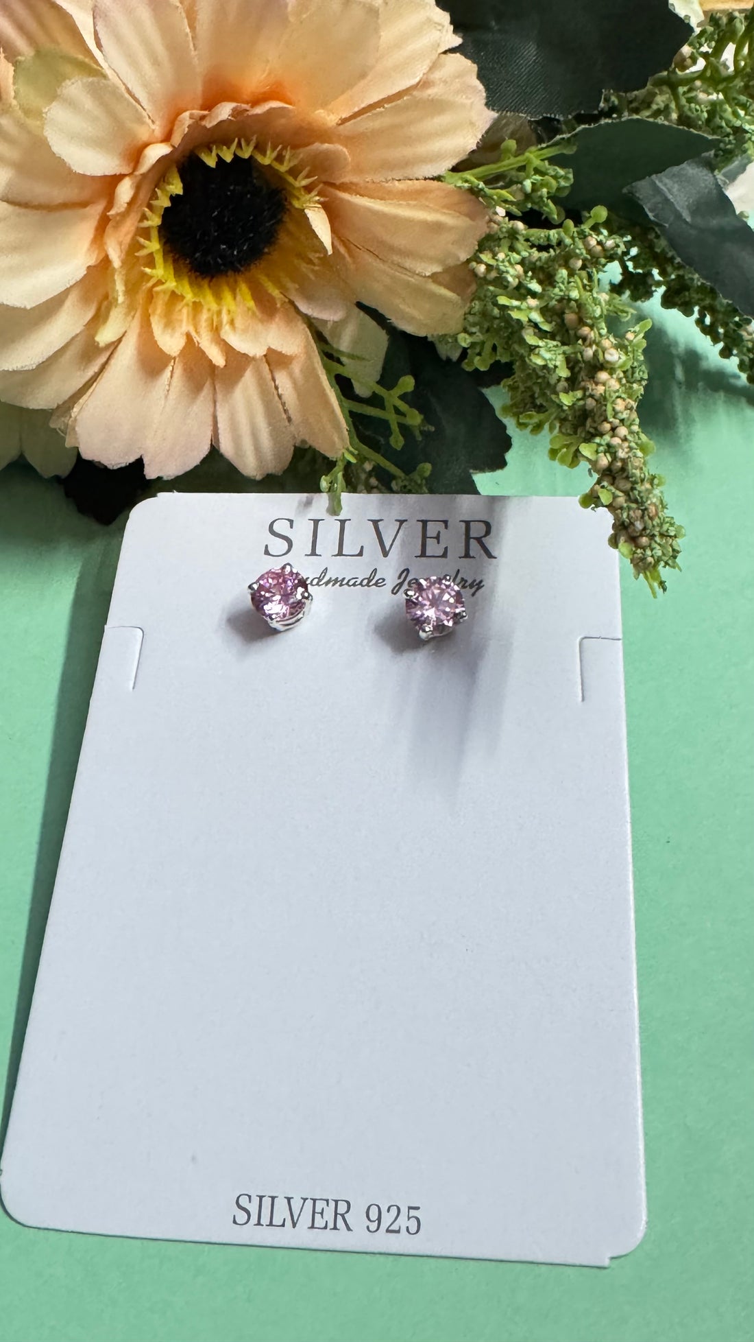 Silver earrings on a card with 'SILVER Handmade Jewelry' text, surrounded by flowers.