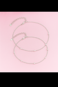 Silver beaded necklace on a pink background
