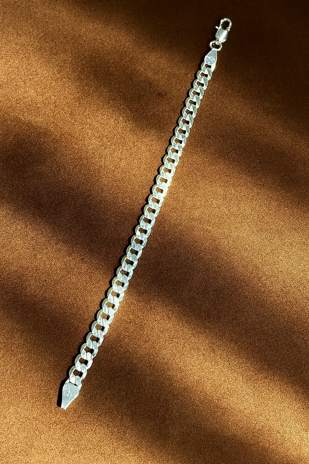 Silver chain bracelet on a brown fabric background