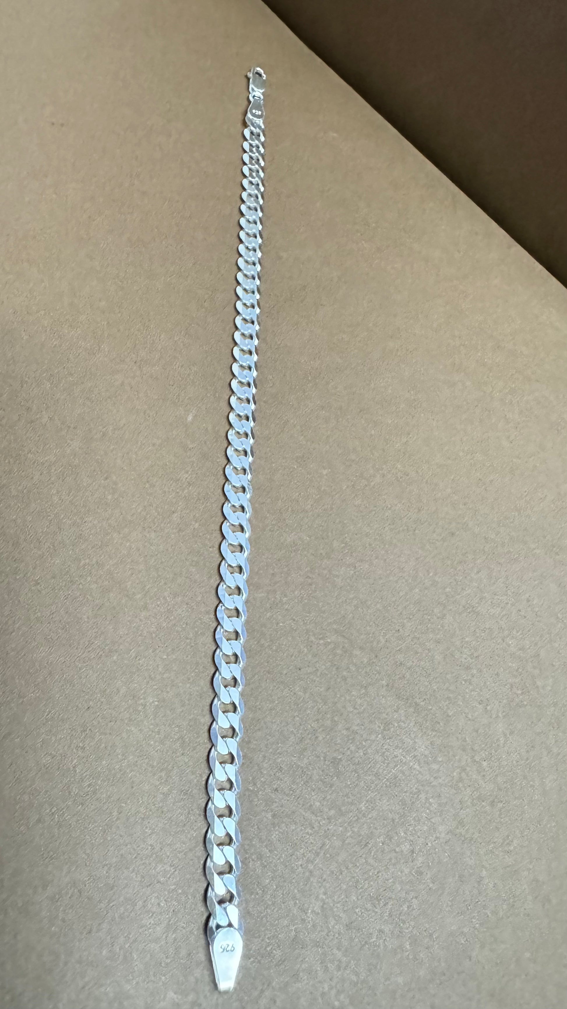 Silver chain bracelet on a beige surface