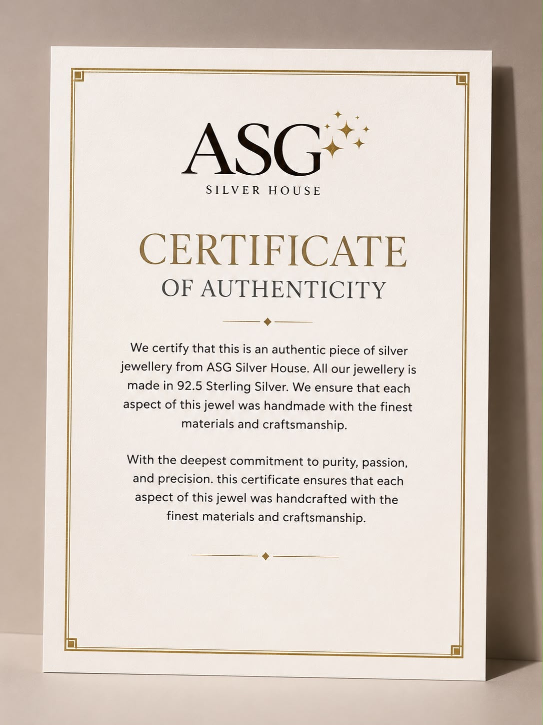 A vertical Certificate of Authenticity card from ASG Silver House, featuring gold decorative borders and text on an off-white background, photographed against a neutral beige backdrop.