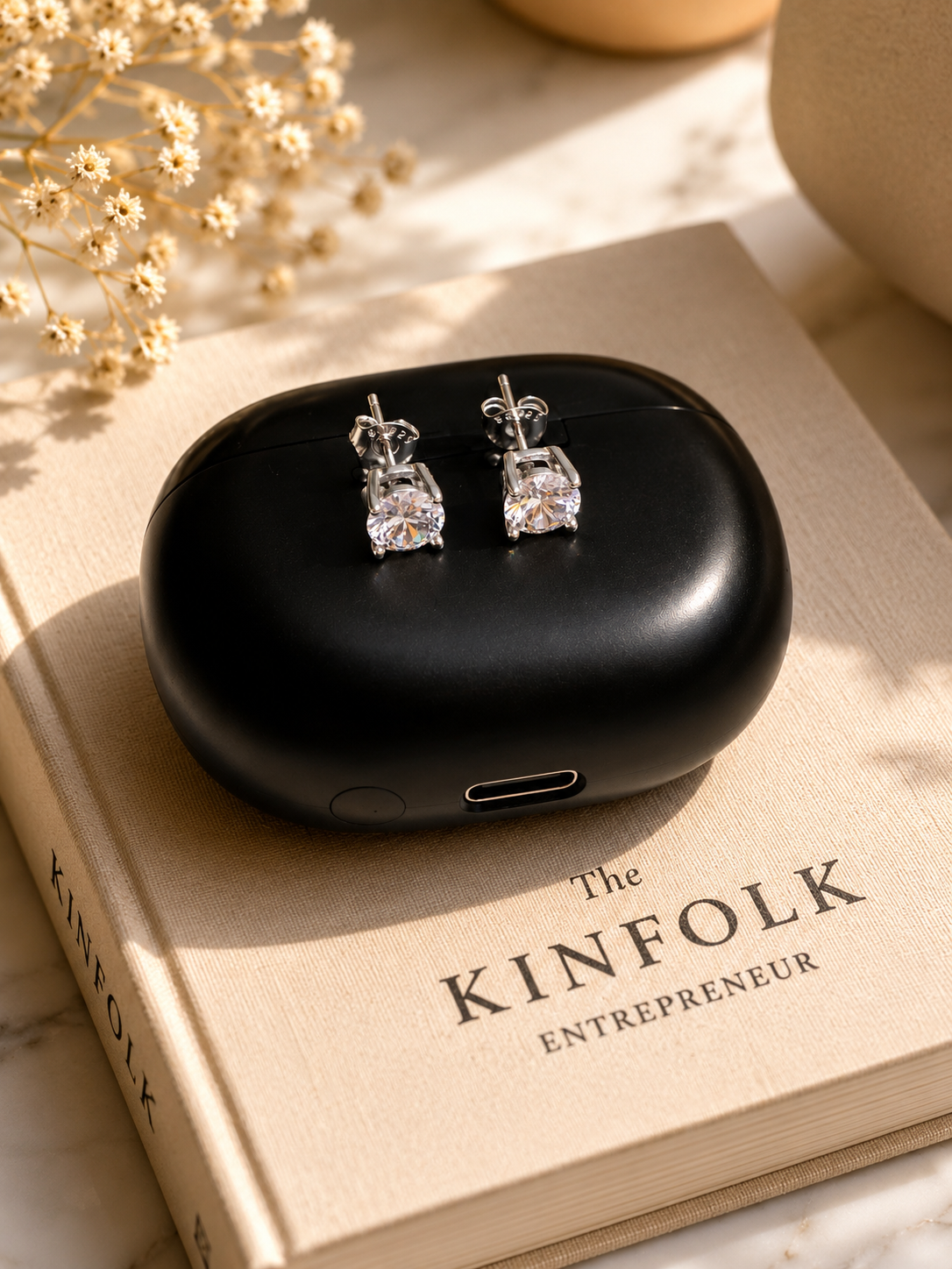 Black earrings case with silver earrings on a Kinfolk book