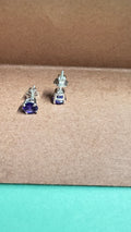 Silver earrings with purple gemstones on a brown surface