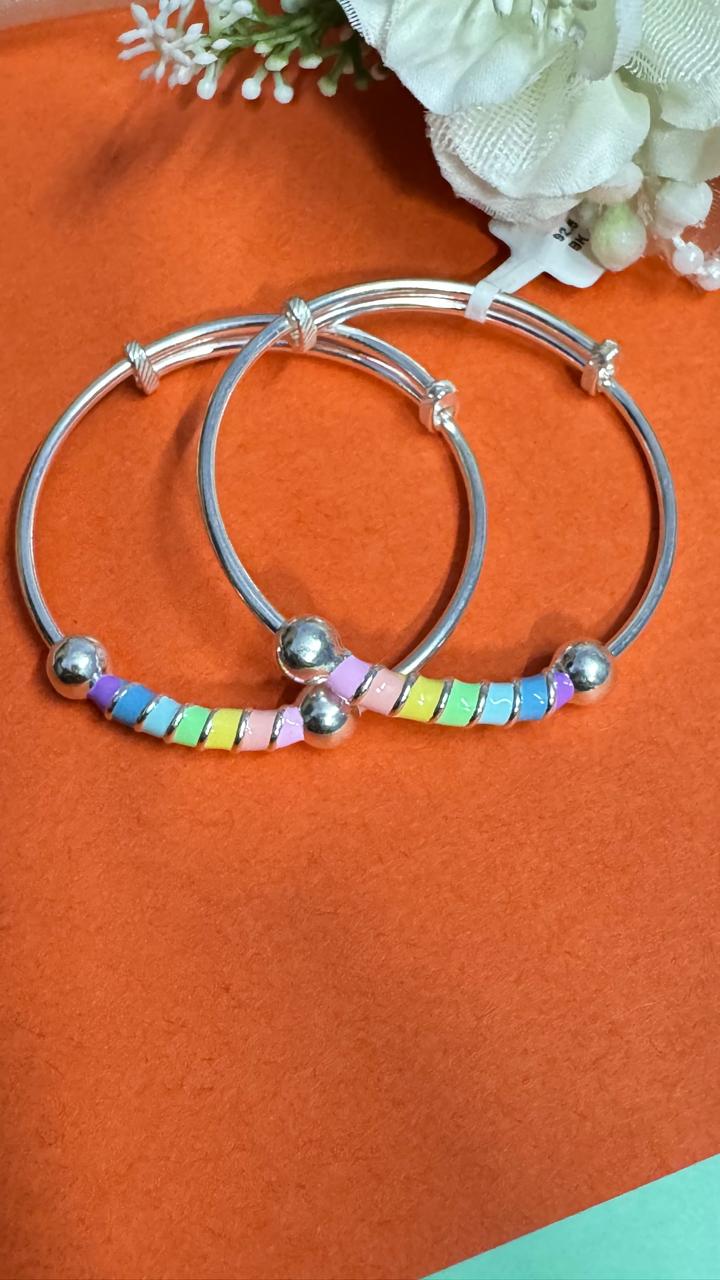 Silver bracelets with colorful beads on an orange background