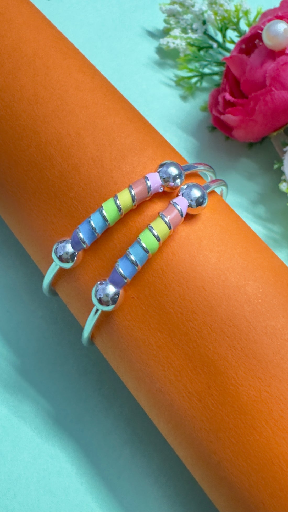 Silver bracelets with colorful beads on an orange background