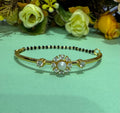Gold bracelet with pearl and gemstone design on a light green background