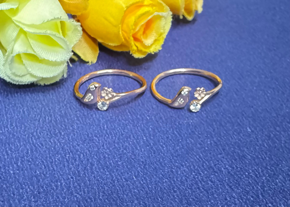 Two gold rings with floral designs on a blue surface with yellow flowers.