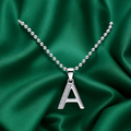 Silver necklace with an 'A' pendant on a green satin background