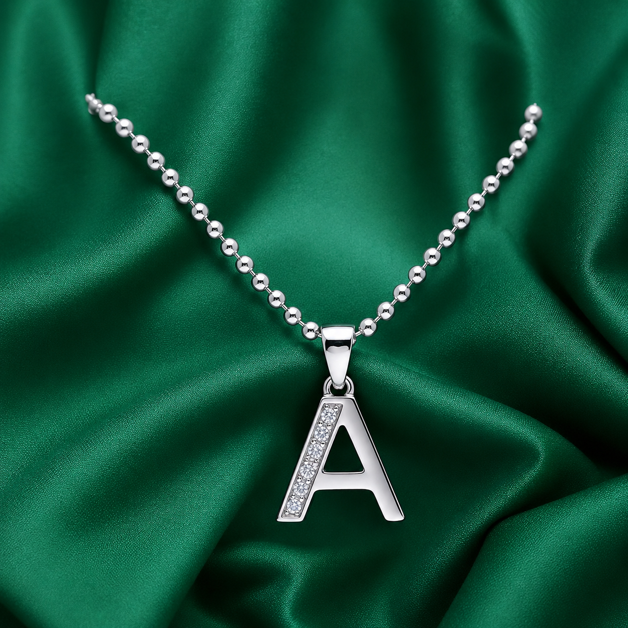 Silver necklace with an 'A' pendant on a green satin background