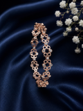 Luxury rose gold bracelet flat lay with navy blue satin and white flowers