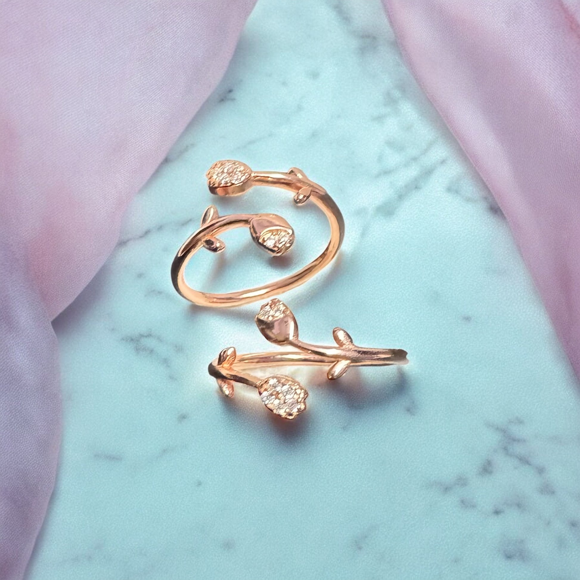 Rose gold ring with floral design on a marble surface