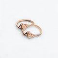 Rose gold ring with floral design and small diamonds on a light gray background