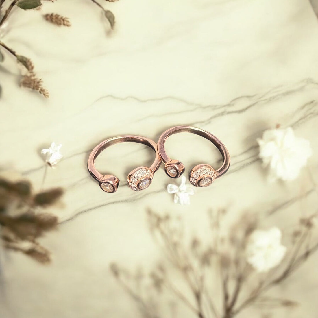 Two rose gold rings with gemstones on a light green background