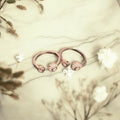 Rose gold hoop earrings on a marble surface with floral decorations