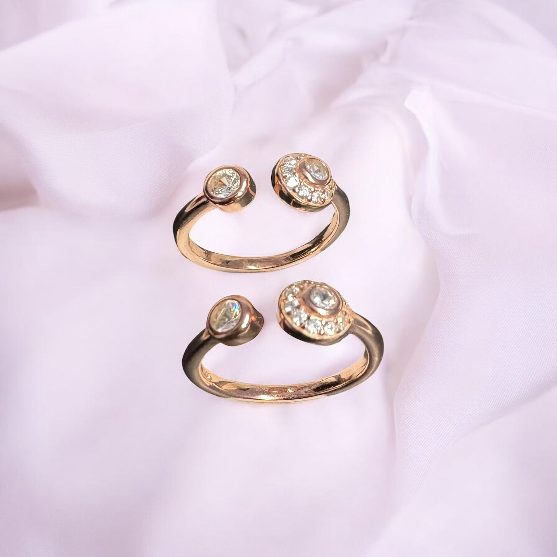 Set of three rose gold rings with gemstones on a light pink fabric background