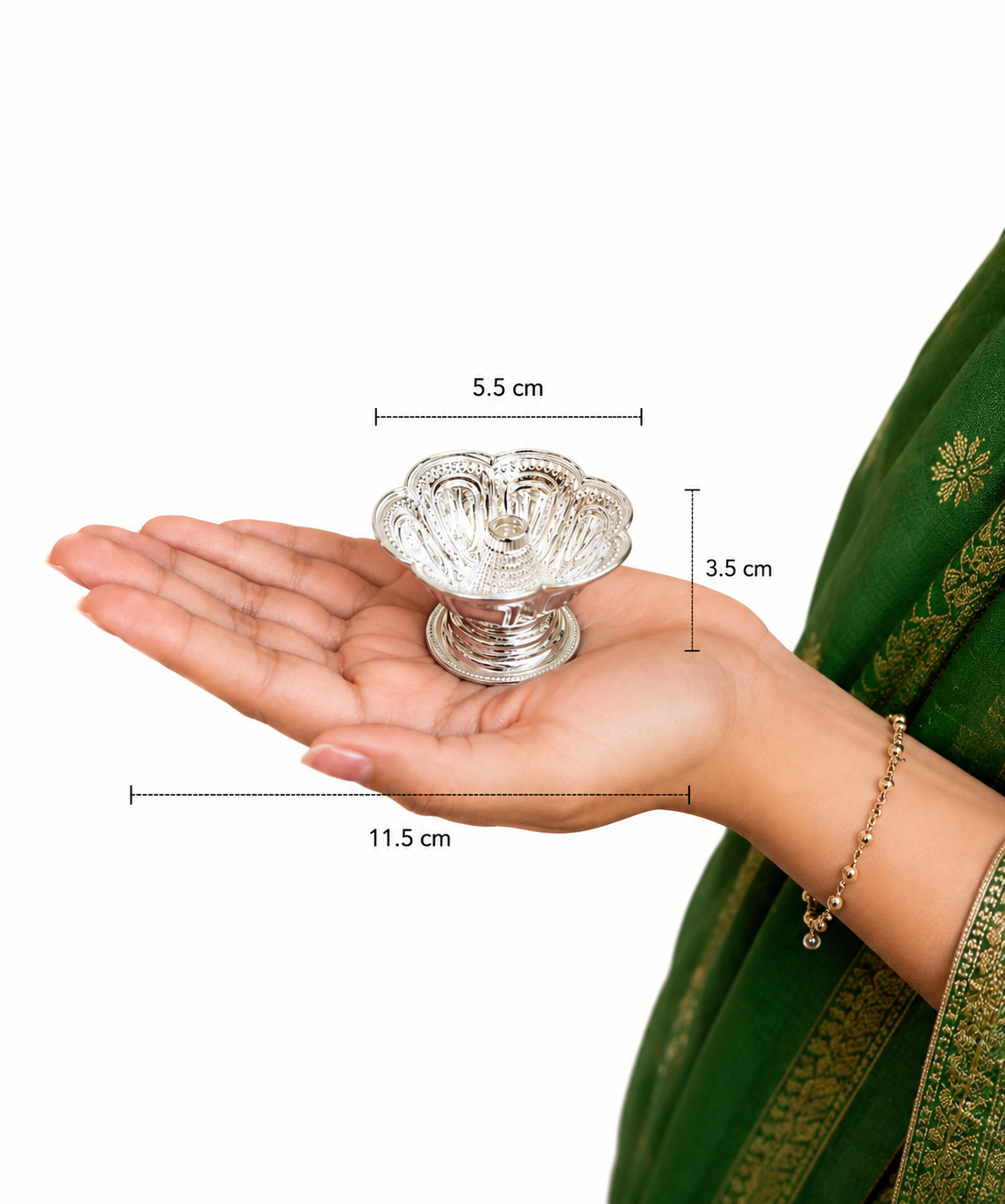 Silver decorative item on a hand with measurements, wearing a green saree.
