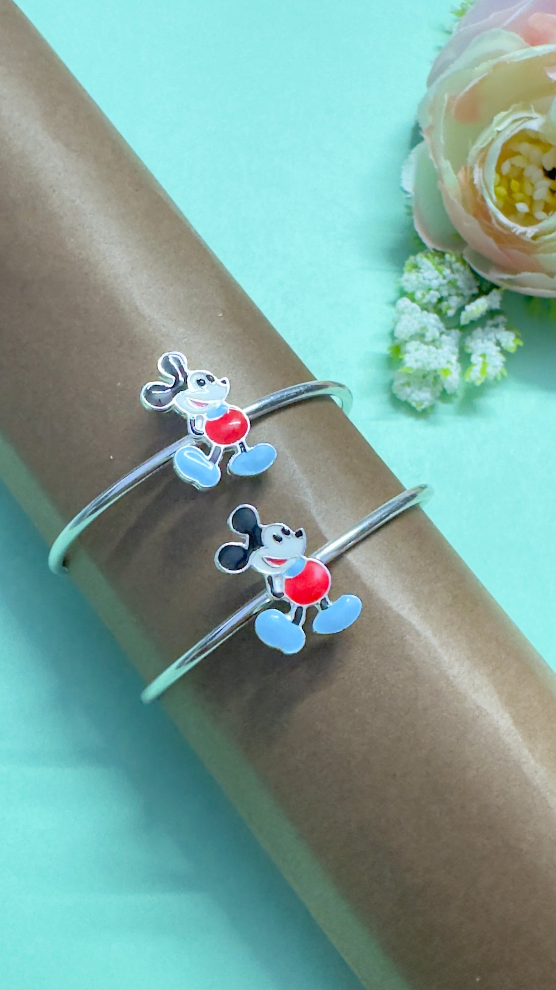 Two silver bangles with cartoon character designs on a light blue background