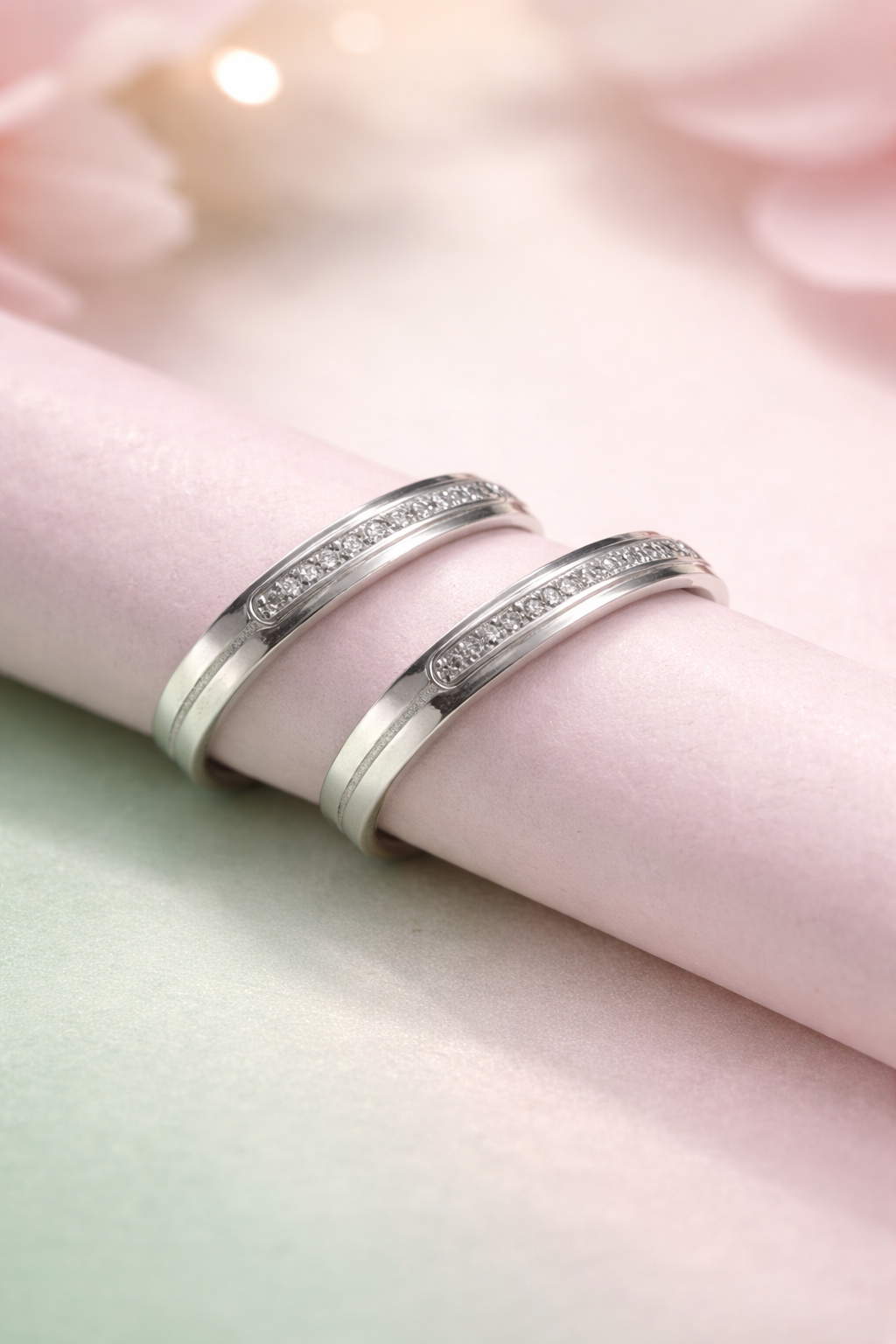 Two silver rings with embedded stones on a soft pink fabric background