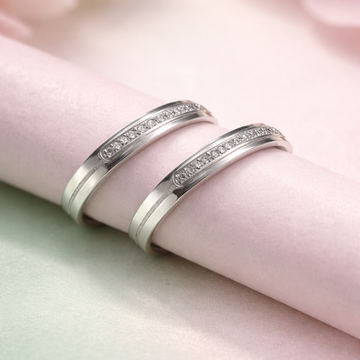 Two silver rings with embedded stones on a soft pink fabric background