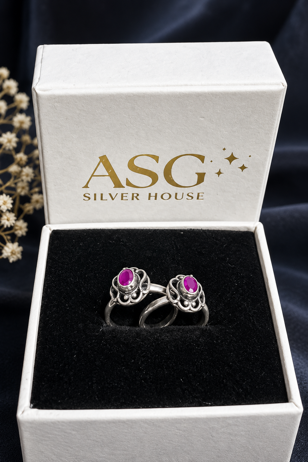 Two silver rings with oval pink gemstones displayed in an open white ASG Silver House gift box with a black velvet insert.