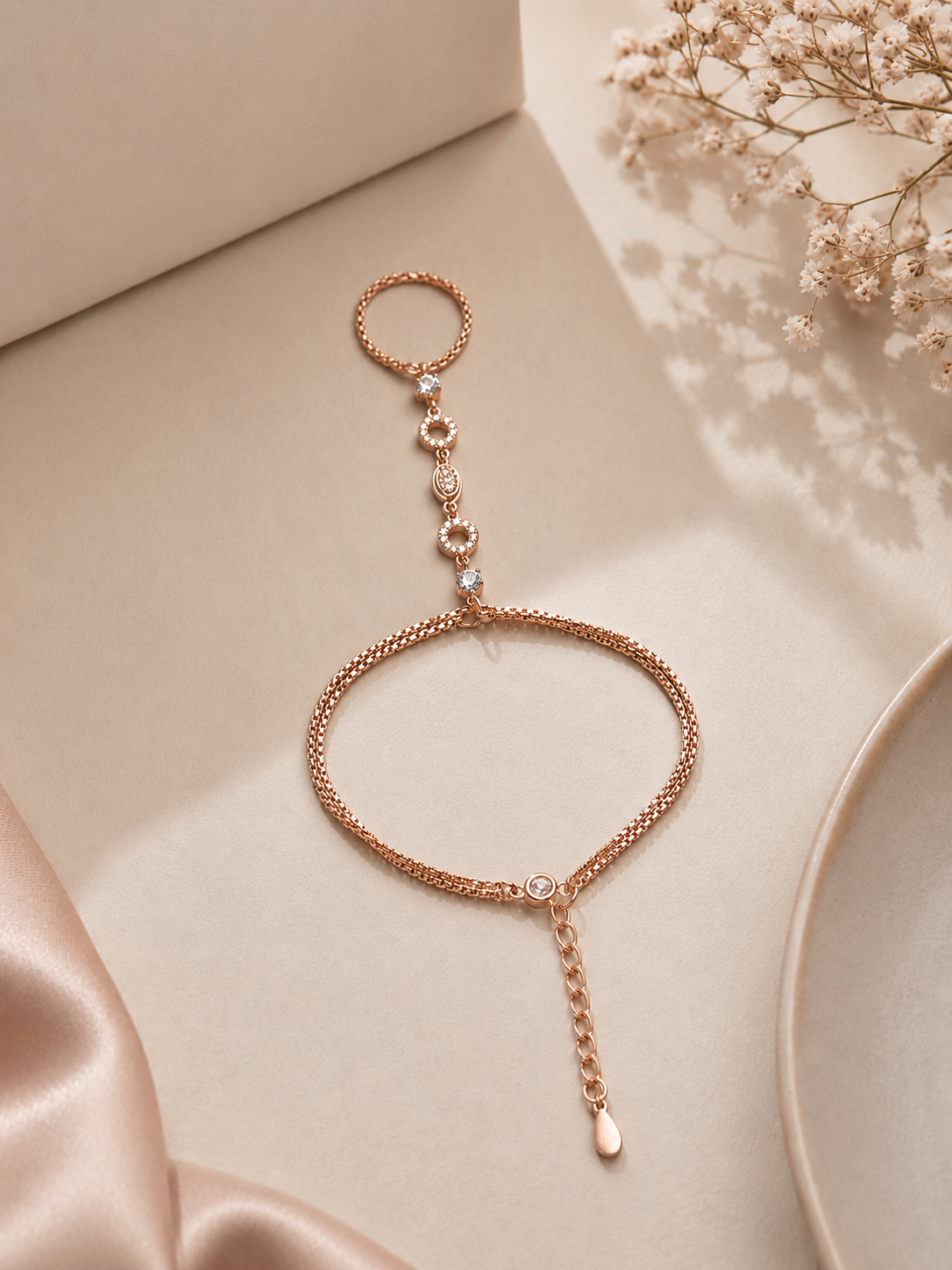 Rose gold bracelet on a beige surface with dried flowers