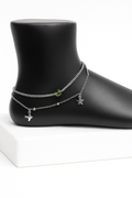 Ankle bracelet with charms on a black mannequin foot against a white background