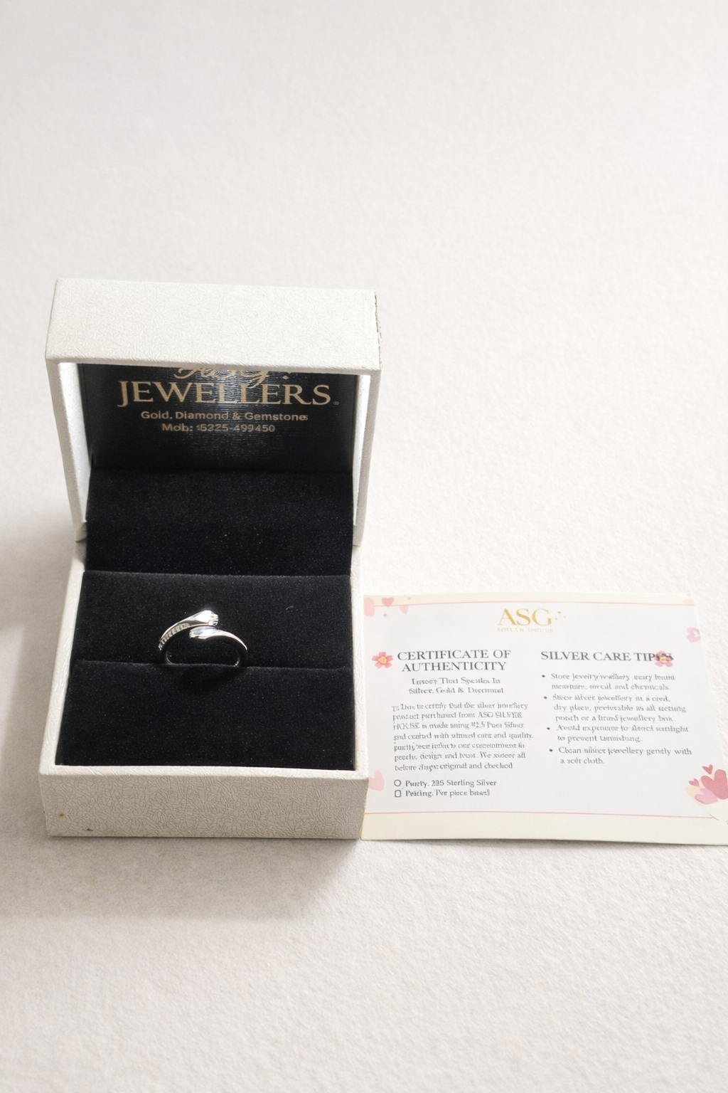 Silver ring in a jewelry box with 'Jewellers' branding on a white background