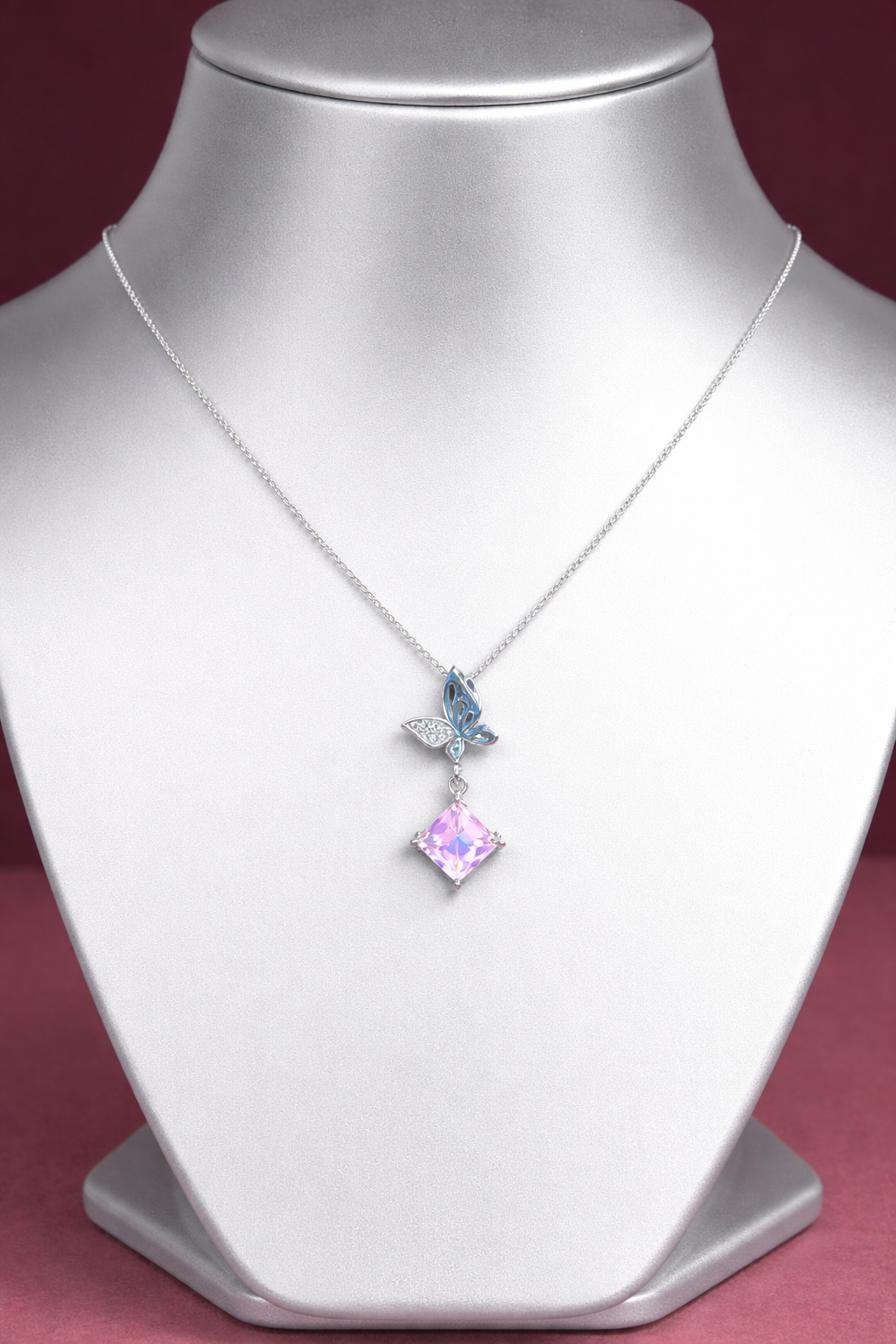 Necklace with a pink gemstone and butterfly pendant on a person wearing a pink top.