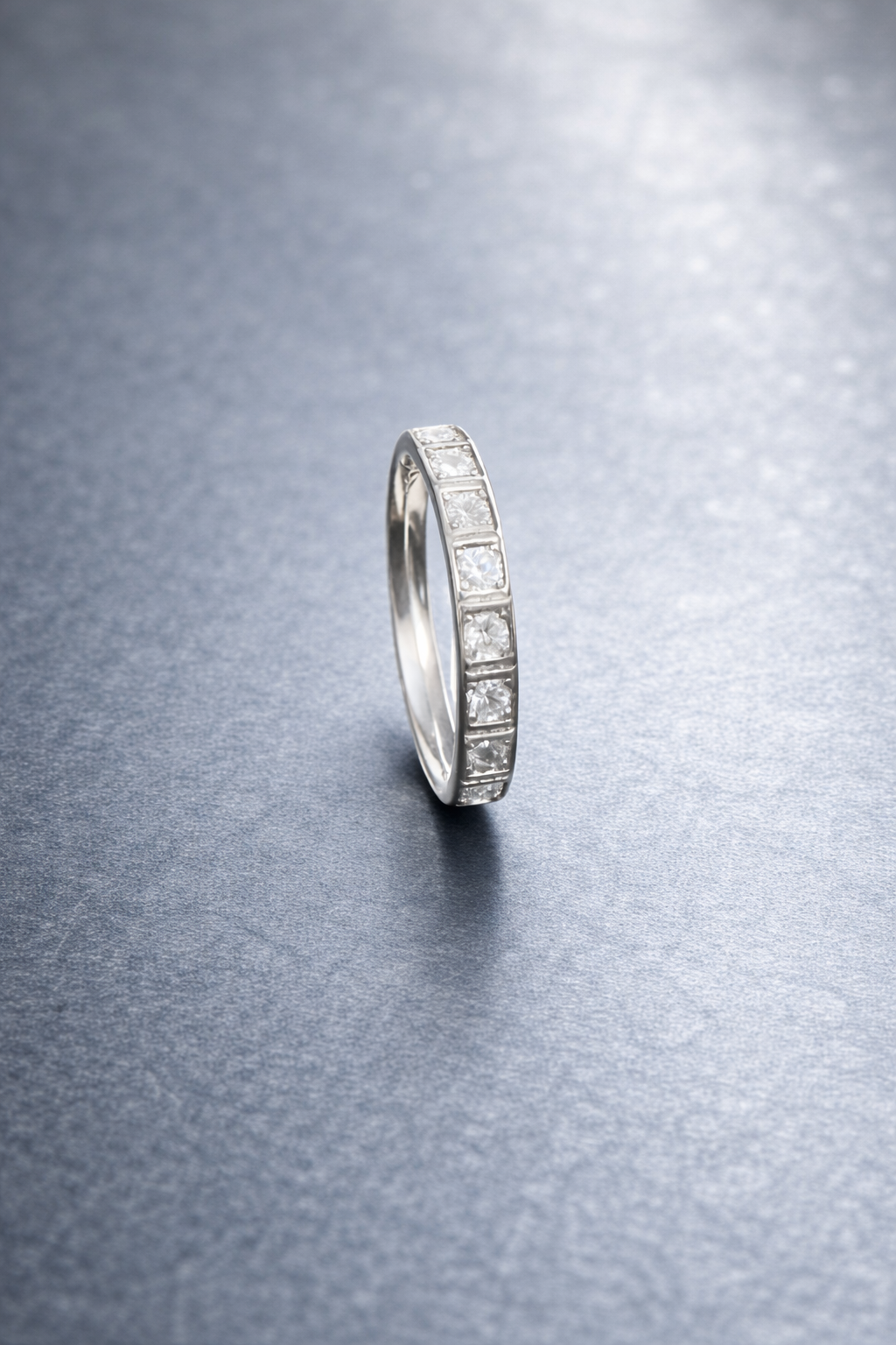 Silver ring with embedded stones on a textured gray surface