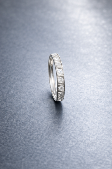 Silver ring with embedded stones on a textured gray surface