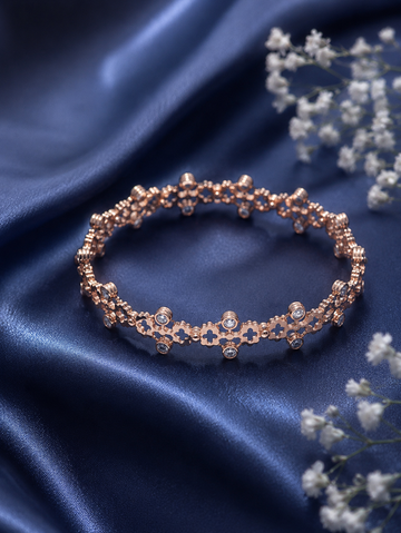 Rose gold floral bracelet on royal blue satin background with sparkling stones