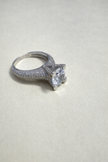 Silver ring with a large central gemstone on a light gray background