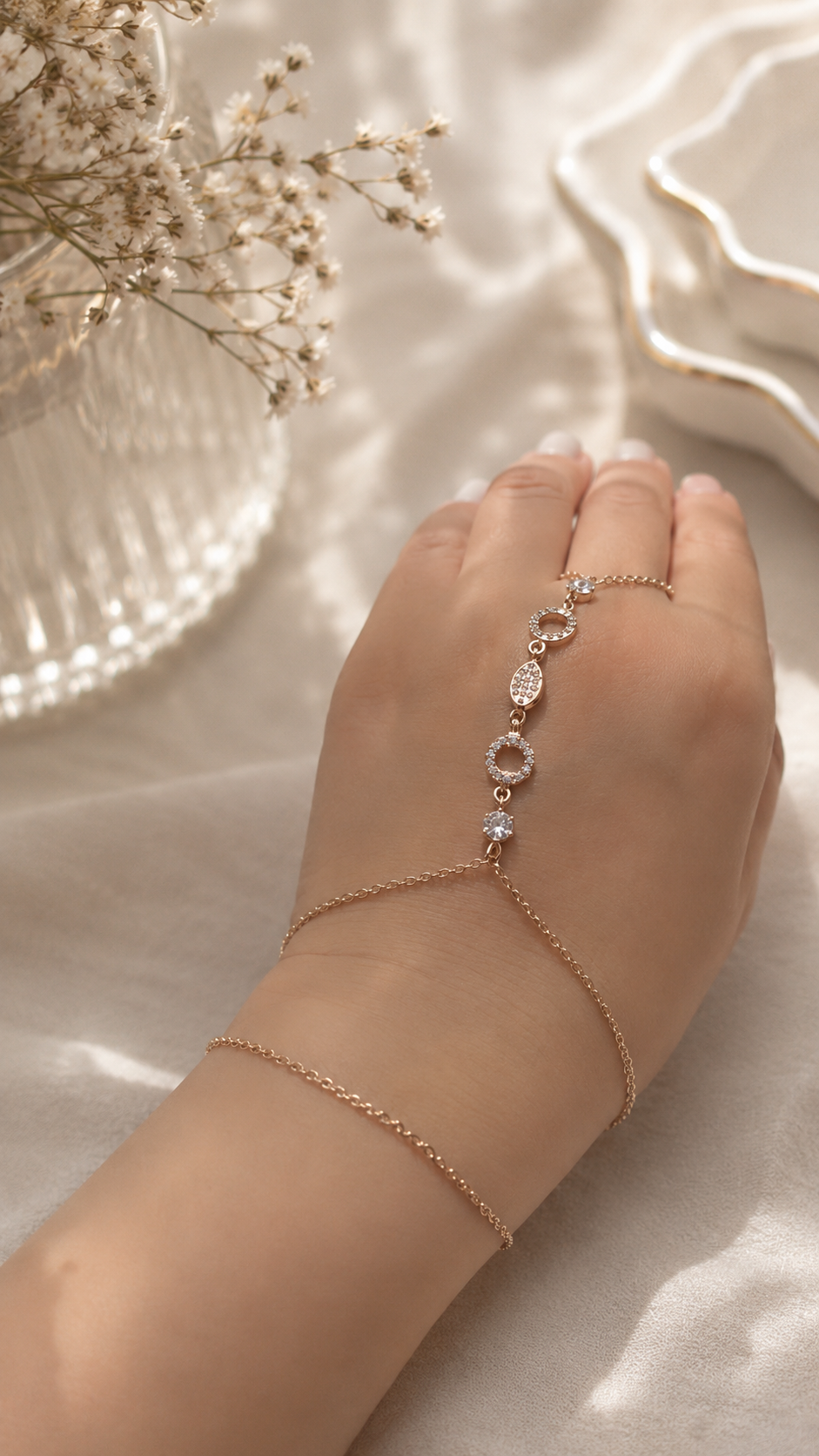 Rose gold bracelet on a beige surface with dried flowers