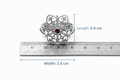 Silver brooch with a red gemstone next to a ruler showing its dimensions on a white background