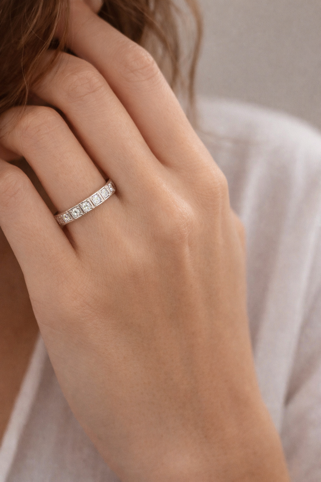 Close-up of a hand wearing a diamond ring with a neutral background